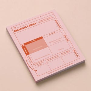 May include: A pink notepad with a grid layout for organizing tasks. The notepad features the text "Organizate Amiga" and includes sections for urgency and importance, with phrases like "Brain Dump" and "Prioritize."