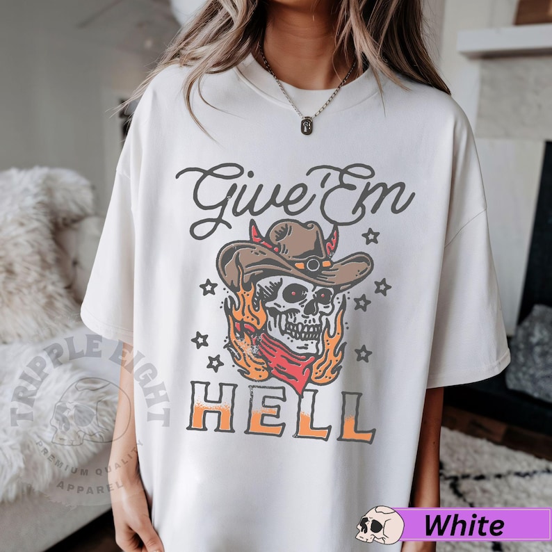 May include: White t-shirt featuring a graphic of a skull wearing a cowboy hat and flames. The text "Give 'Em Hell" is printed below the skull.