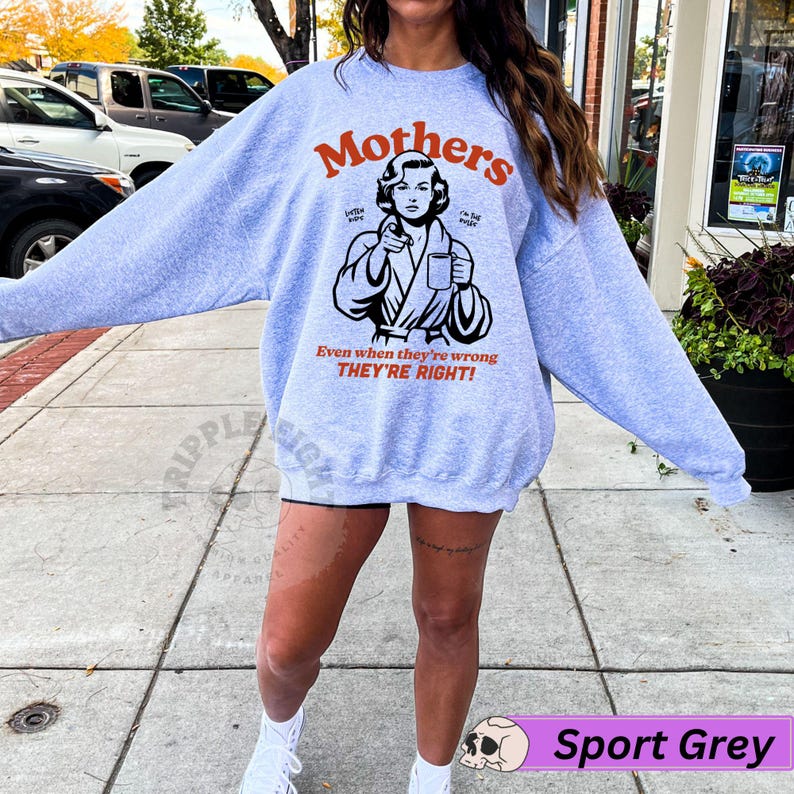 Op de afbeelding: Een grijs sweatshirt met een afbeelding van een vrouw in een badjas die een kop koffie vasthoudt. De tekst op het sweatshirt luidt "Mothers Even when they're wrong THEY'RE RIGHT!"