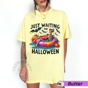 May include: Yellow t-shirt with a skeleton in a donut pool float and the text "Just Waiting for Halloween".
