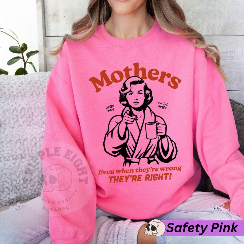 Op de afbeelding: Roze sweatshirt met een afbeelding van een vrouw in een badjas die een kop koffie vasthoudt. De tekst "Mothers" staat in oranje boven de afbeelding en de tekst "Even when they're wrong THEY'RE RIGHT!" staat onder de afbeelding.