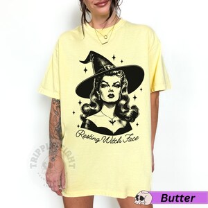 May include: A yellow t-shirt with a black and white illustration of a witch with the text "Resting Witch Face".