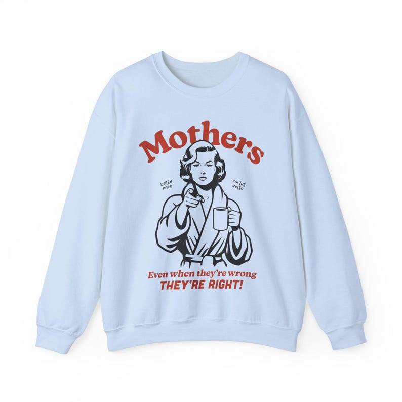 Op de afbeelding: Lichtblauwe trui met een zwart-witte illustratie van een vrouw in een badjas die een mok vasthoudt. De tekst "Mothers" staat in rode letters boven de illustratie. De tekst "Listen Kids I'm the Boss" staat in kleinere rode letters onder de illustratie. De tekst "Even when they're wrong THEY'RE RIGHT!" staat in rode letters onder de illustratie.