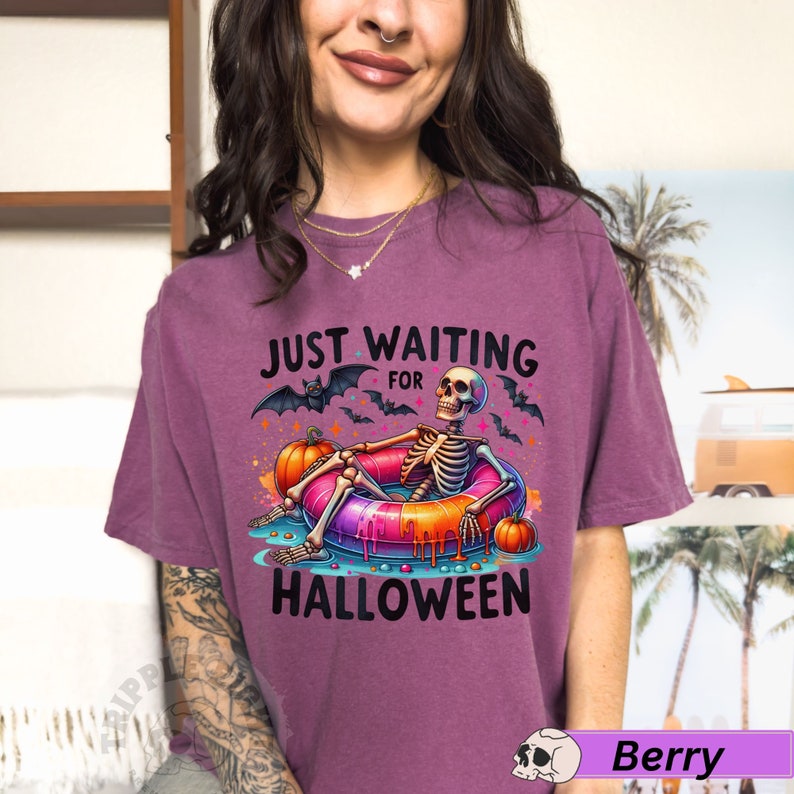 May include: Purple t-shirt with a skeleton in a donut pool float and the text "Just Waiting for Halloween".