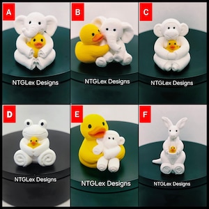 Peut inclure: Une collection de six figurines d'animaux blanches étiquetées de A à F, tenant chacune un petit canard en caoutchouc jaune. Les animaux incluent un éléphant, un singe, une grenouille et un kangourou. Chaque figurine porte le texte NTGLex Designs.
