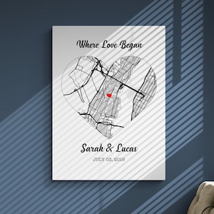 May include: A white canvas print with a black and white map of a city in the shape of a heart. The text "Where Love Began" is at the top of the print. The text "Sarah & Lucas" is below the map. The date "July 03, 2019" is below the names.