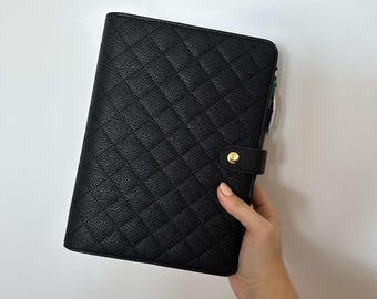 May include: Black leather planner with a quilted pattern and a gold button closure.