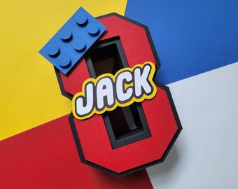 May include: A red number eight with black trim, a blue Lego brick, and the name "JACK" in white letters with a yellow outline. The background is a mix of yellow, red, blue, and white.