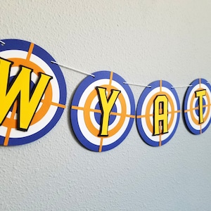 May include: A blue and orange target-themed banner with the name "WYATT" spelled out in yellow letters.