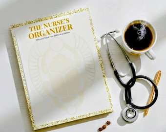 May include: A white notebook titled "THE NURSE'S ORGANIZER" with gold accents, a stethoscope, a cup of coffee, and a pen. The notebook has a gold dotted border and a large design on the cover. Coffee beans are scattered on the white surface.