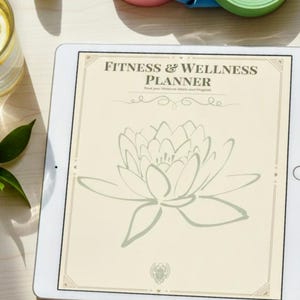 May include: A white tablet displaying a "Fitness & Wellness Planner" with a lotus flower illustration. Rolled exercise bands in pink, blue, and green are in the background. A pen and a glass of water with lemon are also visible.