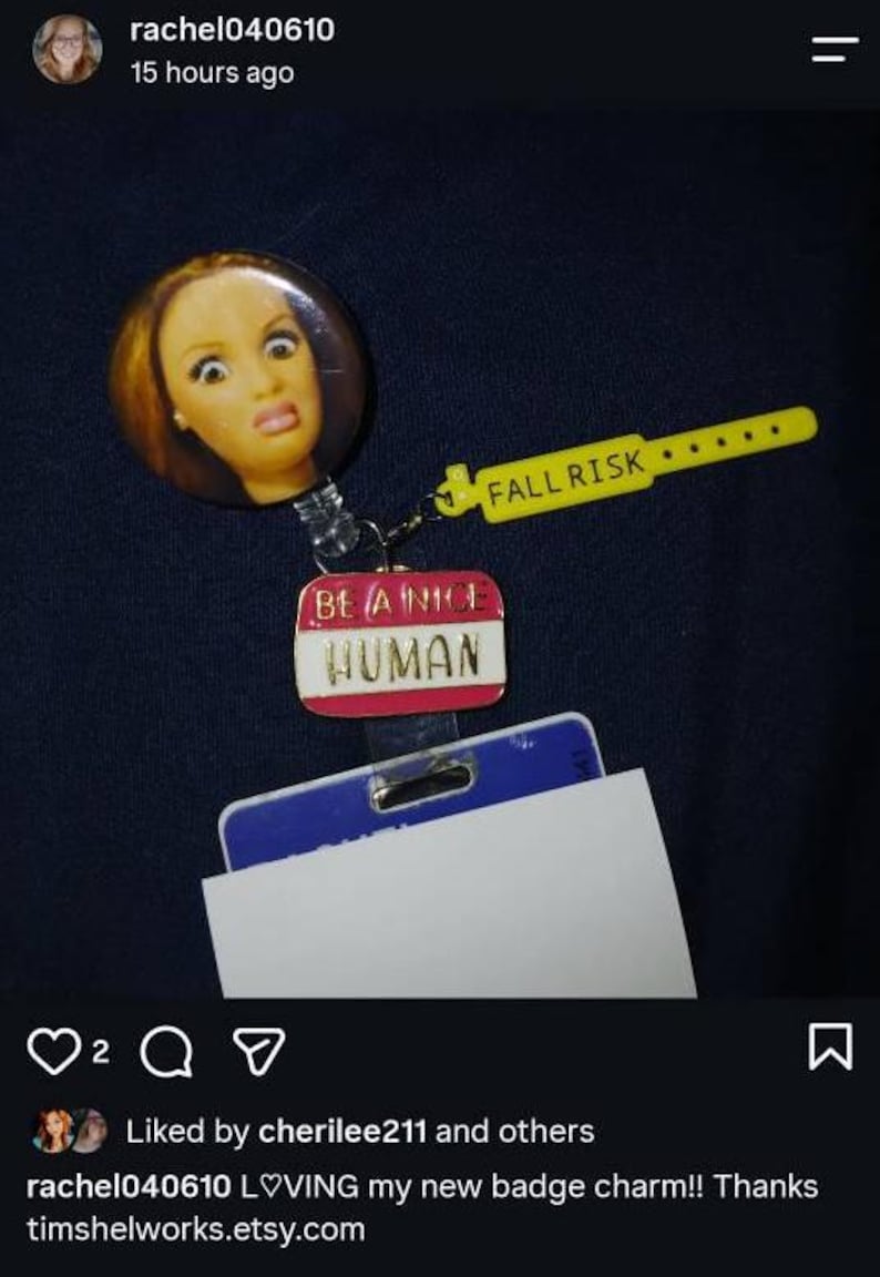 Peut inclure: Un enrouleur de badge avec un bouton circulaire repr&eacute;sentant un visage de poup&eacute;e, une breloque en plastique jaune avec le texte FALL RISK et une breloque &eacute;maill&eacute;e rose et blanche avec le texte BE A NICE HUMAN, fix&eacute; &agrave; un porte-badge bleu et blanc.