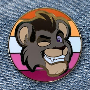 Może przedstawiać: Okrągła przypinka z kreskówkową głową lwa w złotej ramce. Lew mruga okiem i ma fioletowe oko. Tło to wielowarstwowy okrąg w kolorze pomarańczowym, białym, różowym i fioletowym.