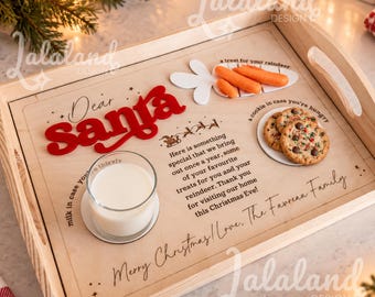 May include: A rectangular wooden serving tray featuring a printed Christmas message for Santa, including the text Dear Santa, a glass of milk, two chocolate chip cookies on a small plate, and three orange carrots shaped like a reindeer treat.