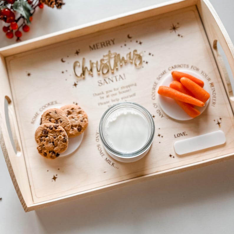 May include: A wooden tray with the words "Merry Christmas Santa!" engraved on it. The tray has three compartments, one with cookies, one with milk, and one with carrots. The tray is decorated with stars and moons.