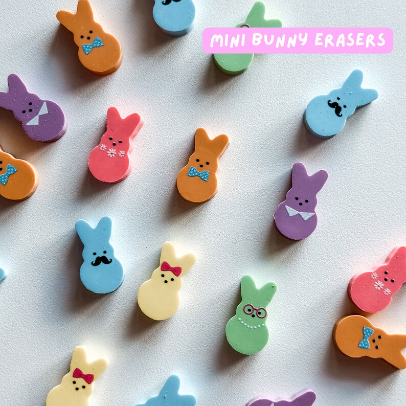 May include: A collection of colorful mini bunny erasers in various designs, including a blue bunny with a mustache, a pink bunny with flowers, and a green bunny with glasses. The erasers are arranged on a white surface with the text "MINI BUNNY ERASERS" in pink letters.