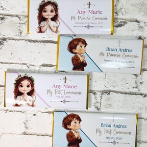 Puede incluir: Envoltorios de barras de chocolate con ilustraciones de niños y texto. Los envoltorios presentan a una niña con una corona de flores y a un niño con traje, ambos con las manos juntas en oración. El texto incluye "Any Marie" y "Brian Andres", con "My First Communion" y la fecha.