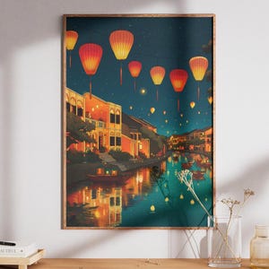 May include: A framed art print depicts a nighttime scene of a canal lined with buildings, illuminated by glowing orange lanterns. The water reflects the lights and buildings, creating a serene and atmospheric landscape.