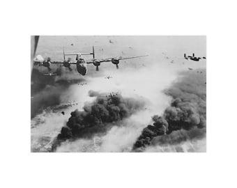 Może przedstawiać: Czarno-białe zdjęcie formacji bombowców B-24 Liberator lecących w szyku bojowym nad celem, który jest zasłonięty przez dym i pył. Bombowce lecą w zwartym szyku, z prowadzącym bombowcem w środku kadru. Dym i pył z nalotu bombowego unoszą się w powietrzu, zasłaniając cel.