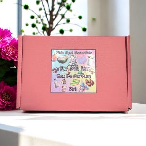 May include: A pink box with a sticker that says "Pixie Spell Essentials TRY ME KIT Eau De Parfum 5ml". The sticker has a colorful design with cartoon images of animals and objects.