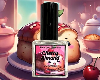 Könnte beinhalten: Eine durchsichtige Glasflasche mit Kirsch-Mandel-Eau de Parfum von Pixie Spell Essentials. Die Flasche ist mit einer Cartoon-Illustration eines Kirsch-Mandel-Gebäcks beschriftet. Die Flasche ist 0,5 fl oz / 15 ml.