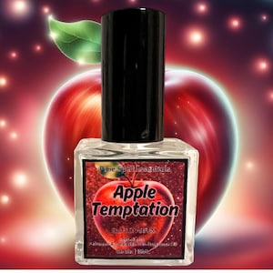 Puede incluir: Una botella de vidrio transparente con una tapa negra y un diseño de manzana roja. La etiqueta dice "Pixie Spell Essentials Apple Temptation Eau de Parfum 1 oz / 30 ml".
