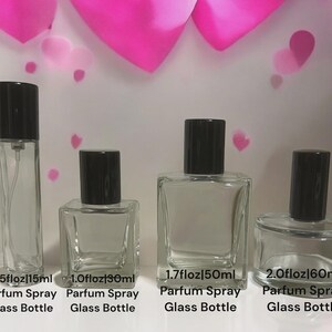 May include: Four clear glass perfume bottles with black caps, labeled 0.5 fl oz (15ml), 1.0 fl oz (30ml), 1.7 fl oz (50ml), and 2.0 fl oz (60ml). Each bottle is labeled "Parfum Spray Glass Bottle". Pink heart decorations are in the background.