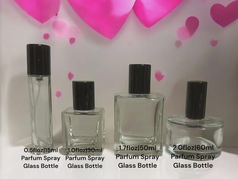 May include: Four clear glass perfume bottles with black caps, labeled 0.5 fl oz (15ml), 1.0 fl oz (30ml), 1.7 fl oz (50ml), and 2.0 fl oz (60ml). Each bottle is labeled "Parfum Spray Glass Bottle". Pink heart decorations are in the background.