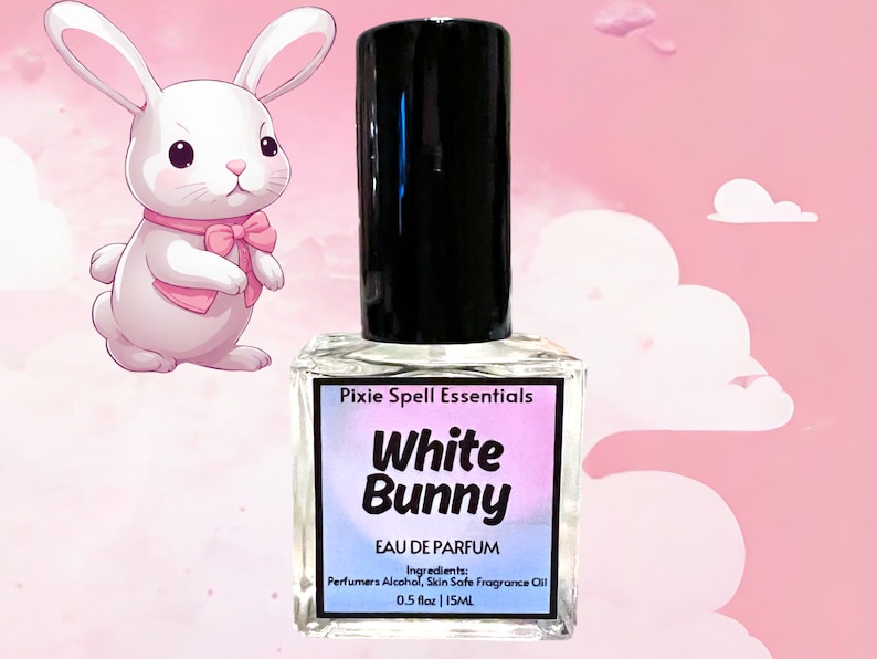 May include: A clear glass bottle with a black cap and a white label. The label says "Pixie Spell Essentials White Bunny Eau de Parfum Ingredients: Perfumers Alcohol, Skin Safe Fragrance Oil 0.5 fl oz | 15ML".