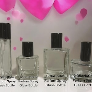 May include: Four clear glass perfume spray bottles with black caps, varying in size from 0.5 fl oz to 2.0 fl oz. Each bottle is labeled with its volume in both fluid ounces and milliliters. The background features pink heart shapes.