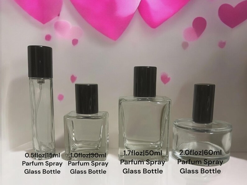 May include: Four clear glass perfume spray bottles with black caps, varying in size from 0.5 fl oz to 2.0 fl oz. Each bottle is labeled with its volume in both fluid ounces and milliliters. The background features pink heart shapes.