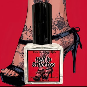 Puede incluir: Un frasco de perfume con tapa negra y etiqueta roja que dice "Hell In Stilettos". El frasco está frente a un fondo rojo con un dibujo de un pie con un tacón de aguja negro con plataforma.
