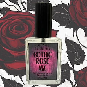 Puede incluir: Una botella de vidrio transparente con una tapa negra y una etiqueta que dice "Pixie Spell Essentials Gothic Rose Eau de Parfum Ing. Perfumers Alcohol Fragrance Oil 0.5 fl oz". La botella está sobre un fondo blanco con un patrón de rosas rojas.