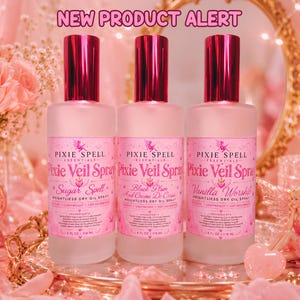 May include: Three frosted glass bottles of Pixie Spell Essentials Pixie Veil Spray, each with a metallic pink cap and a pink label. The labels read Sugar Spell, Black Plum And Creme De Cassis, and Vanilla Worship, with 4 FL OZ | 118 ML printed on each.