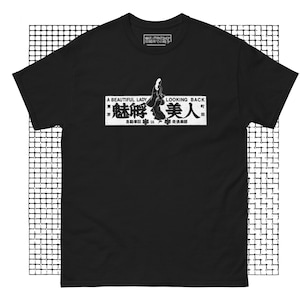 May include: Black t-shirt with a white graphic of a woman walking away with the text "A Beautiful Lady Looking Back" and Japanese characters that read "魅孵美人" (meaning "Beautiful Lady Looking Back") and "自動車狂走倶楽部" (meaning "Automobile Racing Club").