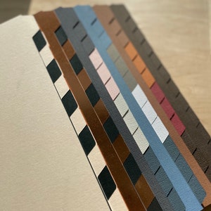 May include: A set of ten colorful paper dividers with different patterns and textures. The dividers are arranged in a fan shape, with the top divider being a black and white checkered pattern. The other dividers are in various shades of brown, gray, blue, and pink.