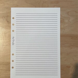 May include: A white lined paper with holes on the left side. The paper has the text "September 2023" written on it.