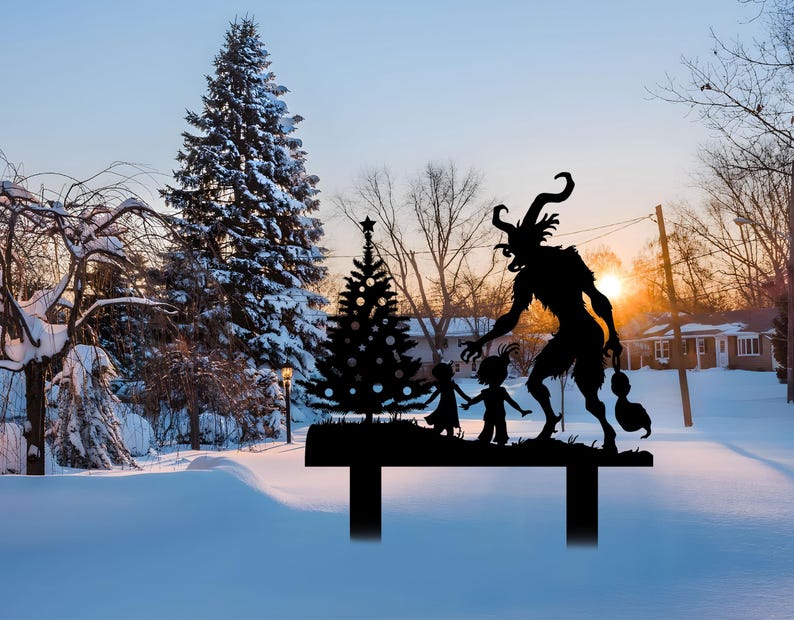 May include: A black metal yard stake featuring a silhouette of Krampus, a horned figure, with children and a Christmas tree. The stake is set in a snowy landscape with a sunset in the background.