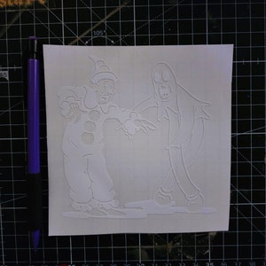 May include: A white vinyl sticker featuring a spooky clown and a ghost. The clown is wearing a hat and has a wide smile. The ghost is wearing a sheet and has a surprised expression.