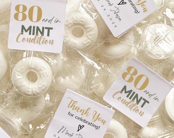 May include: White mint candies in clear wrappers, some with printed labels. The labels read "Thank You for celebrating!" and "80 and in MINT Condition." The date "08.28.2028" is also printed on the labels.