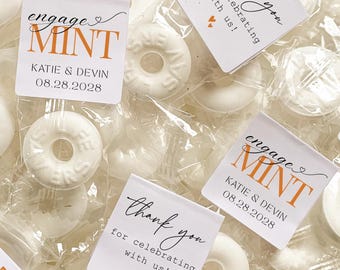 May include: White mint candies in clear packaging, some with small square labels. The labels read "engage MINT" with a couple's names and a date. Other labels say "thank you for celebrating with us!"