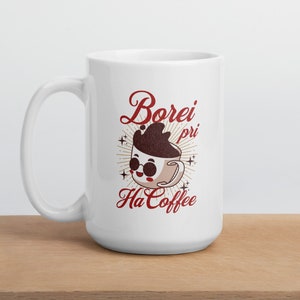 Pode incluir: Caneca de café de cerâmica branca com uma ilustração de desenho animado de uma xícara de café usando óculos de sol e o texto "Borei pri Ha Coffee" em vermelho.