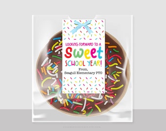 May include: A colourful donut with chocolate icing and sprinkles in a clear plastic bag with a tag that reads "Looking forward to a Sweet School Year! From, Seagull Elementary PTO".