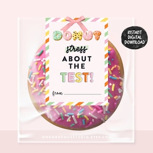 Peut inclure: Un donut glacé rose avec des vermicelles colorés est emballé dans un sac en cellophane transparent. Une étiquette cadeau avec les mots "Donut stress about the test!" est attachée avec un ruban rose. L'étiquette comprend un espace pour écrire "de".