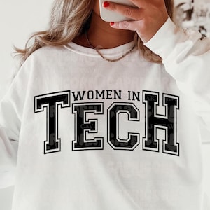 May include: White sweatshirt with black text that reads "Women in Tech" in a varsity style font.