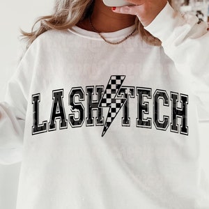 May include: White sweatshirt with black text that reads "LASH TECH" with a black and white chequered lightning bolt graphic.