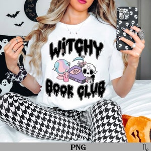 May include: White t-shirt with the text "Witchy Book Club" in a black, bubble-style font. The shirt features a graphic of a crystal ball, a book, a skull, and a candle. The design has pastel colours and a spooky theme.