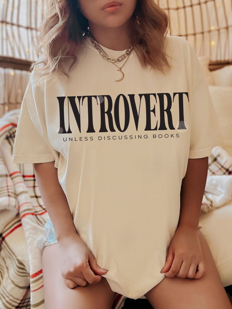 Pode incluir: Uma camiseta branca com o texto "Introvertido a menos que se discuta livros" impresso em preto.