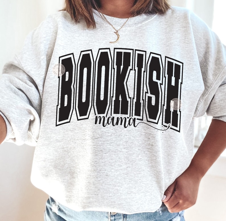 K&ouml;nnte beinhalten: Ein grauer Pullover mit dem Aufdruck "BOOKISH mama" in Schwarz.