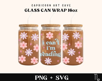 Puede incluir: Tres envoltorios de vidrio para latas con tapas de madera y pajitas transparentes. Las latas están decoradas con flores rosas y moradas y el texto "I can't I'm reading". El texto "Capricorn Art Cave" y "Glass Can Wrap 16oz" están en la parte superior.